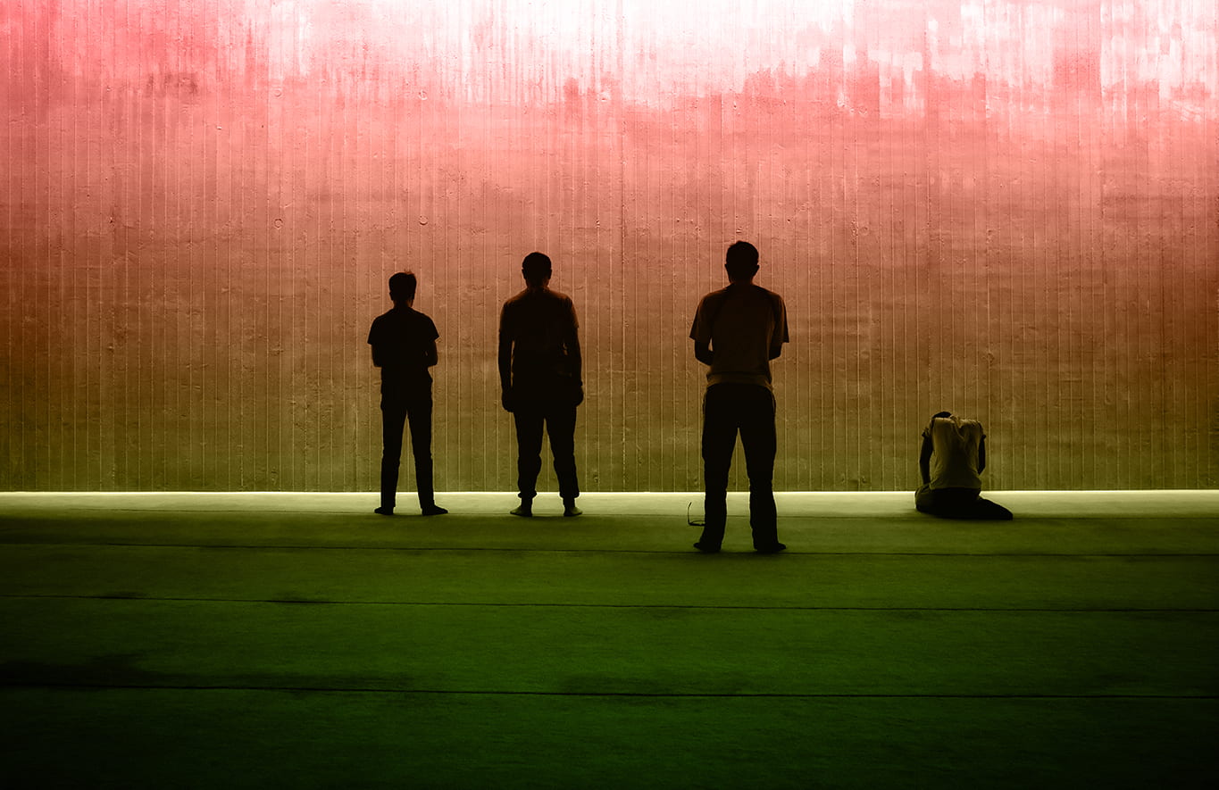 Silhouettes of three standing figures and on kneeling all seen with a muted color background