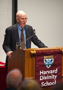 R. Gustav Niebuhr standing behind a podium with a Harvard Divinity School banner on it