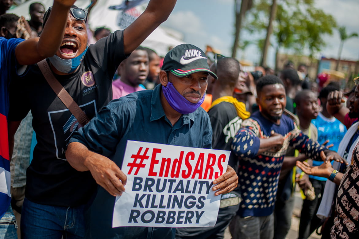 Protestors holding signs "#endSARS Brutality Killings Robbery