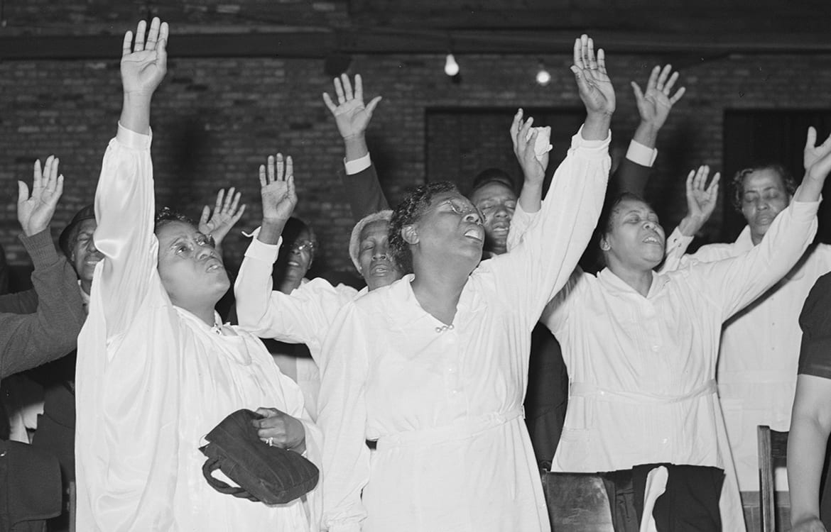 Pnetecostal women with their hands raised in praise fo the Lord during a worship service