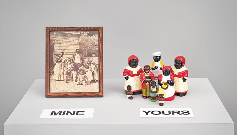 Art installation of a family portrait of an African American family labeled "mine" next to a set of Aunt Jemima figurines labeled "yours"