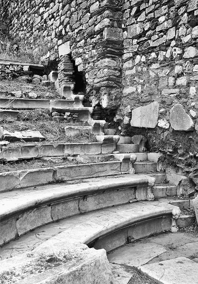 Black and white photo of crumbling stone steps with grass growing among the stones