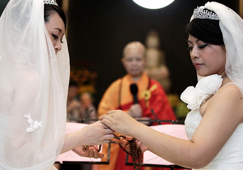 Photo of two brides, with Buddhist nun Chao-hwei in the background, presiding over the wedding ceremony