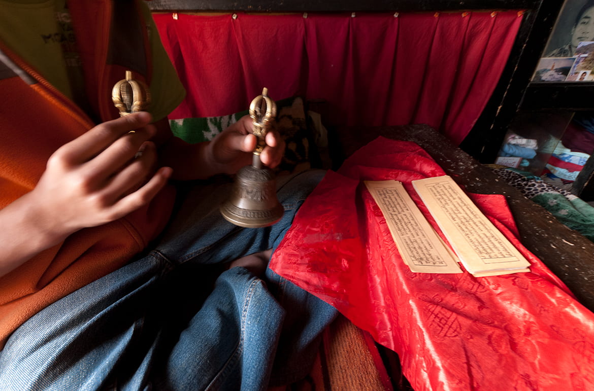 Practitioner holding prayer bells with Buddhist scripture in front of him