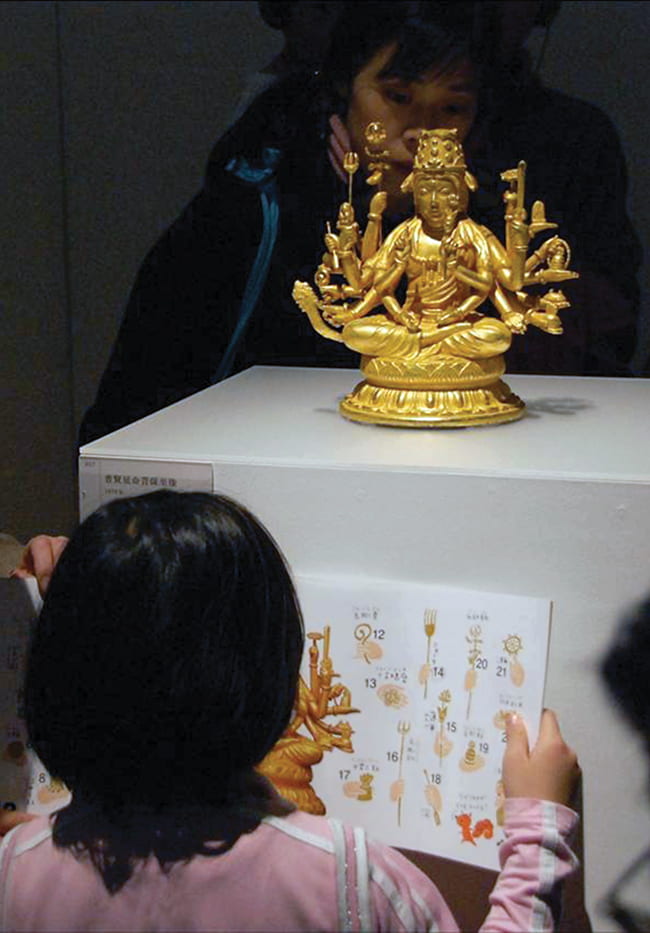Young girl looking at a Buddhist figurine in a museum display