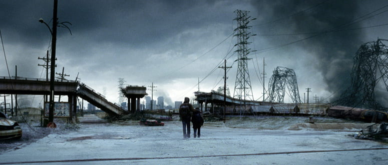 Film still from The Road with two figures walking through through an apocalyptic landscape