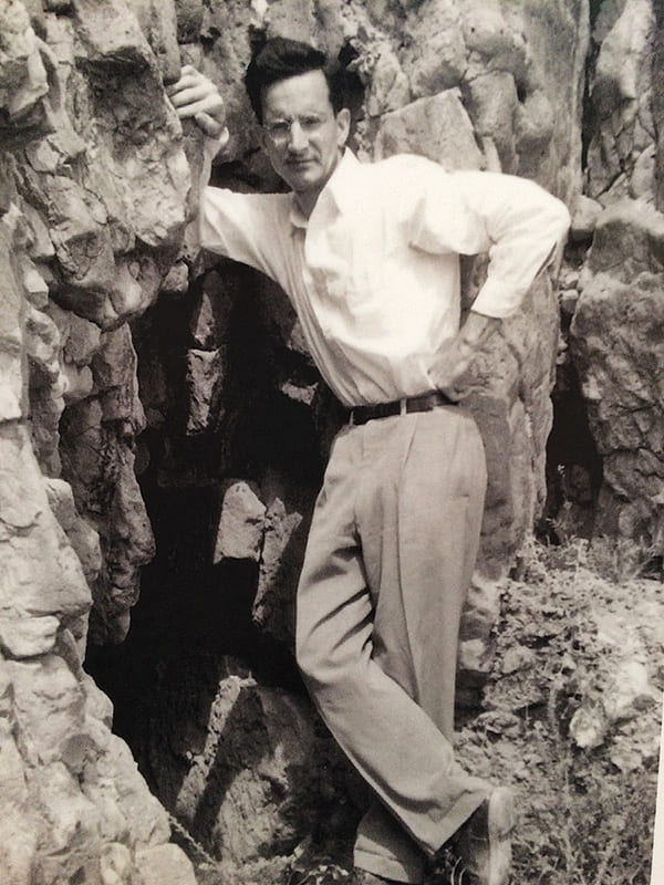 Frank Moore Cross standing in front of a cave