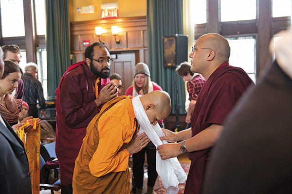 The Karmapa Lama draping a white khata cloth over a monk student's neck in the Braun Room