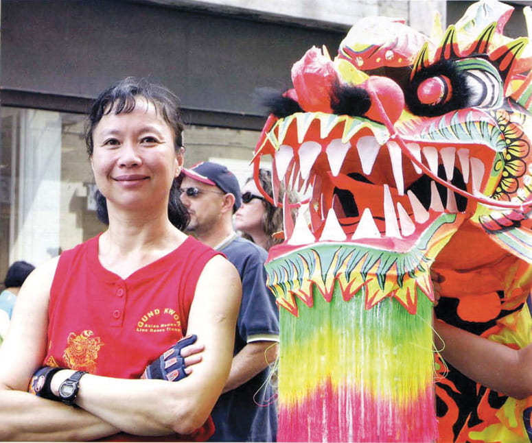 Woman standing next to a colorful dragon dance mask