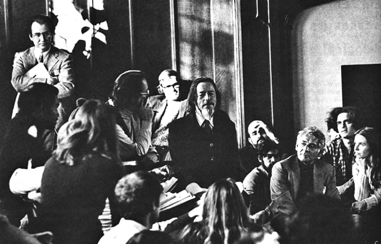 Alan Watts surrounded by students and faculty in the Braun Room