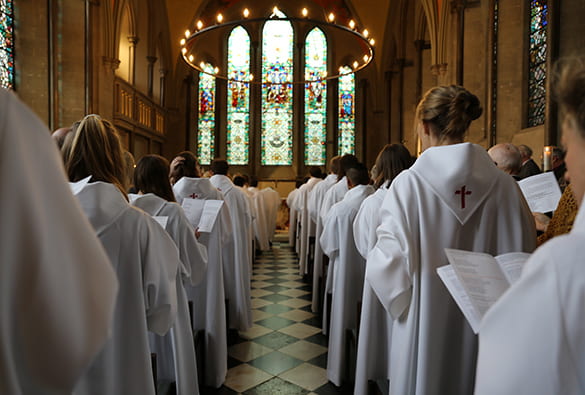 Young adults in white robes standing in worship inside a church sanctuary