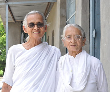 Two women wearing plain white saris