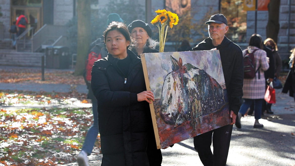 Photo of a the artist and friends carrying a large painting through the Harvard campus