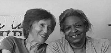 A white woman and Black woman sitting together smiling
